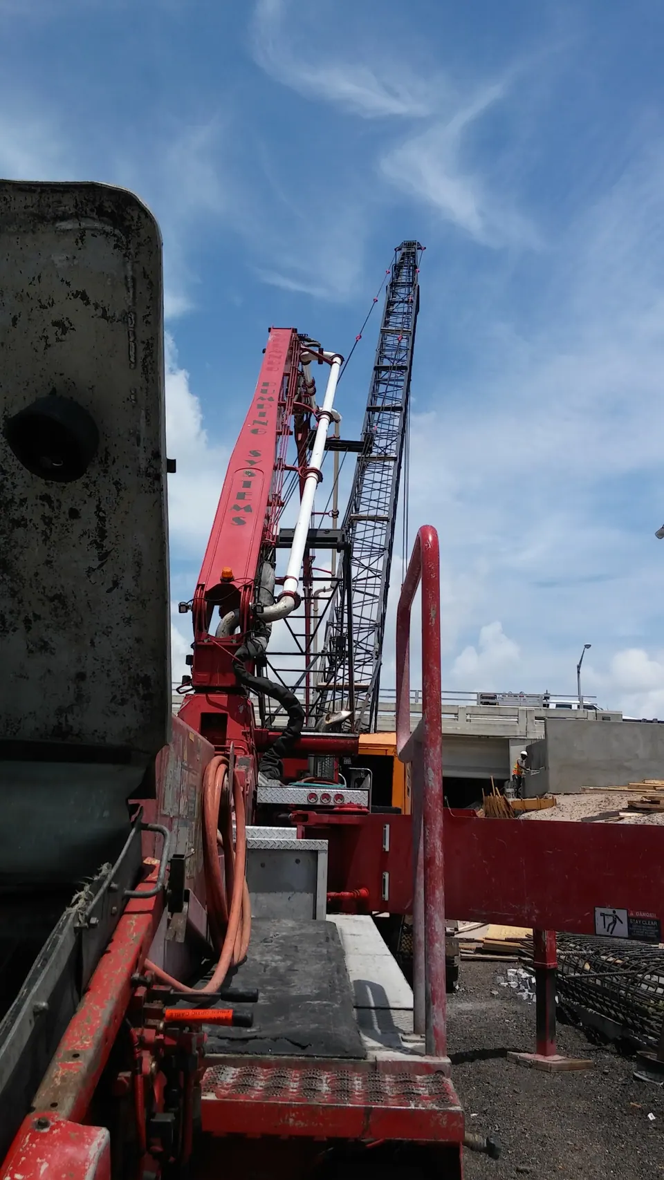 Red boom pump beside a tower crane on a high-rise job