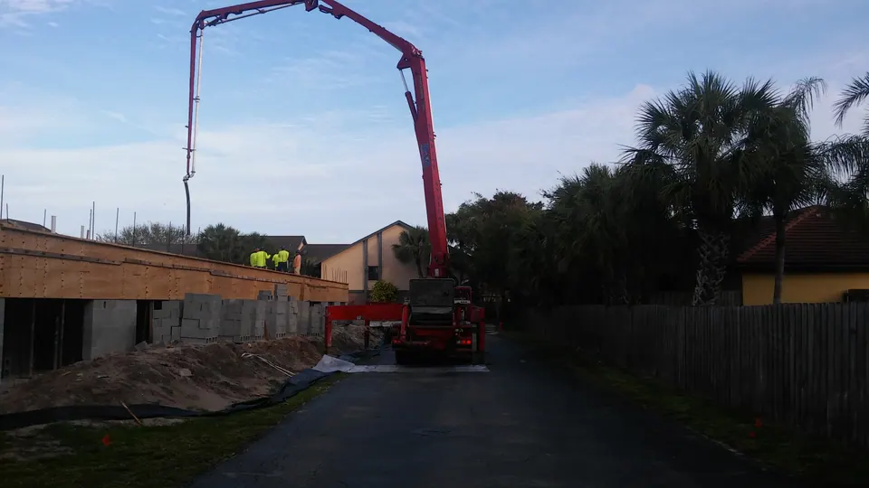 Red boom pump extended over a residential job at dusk